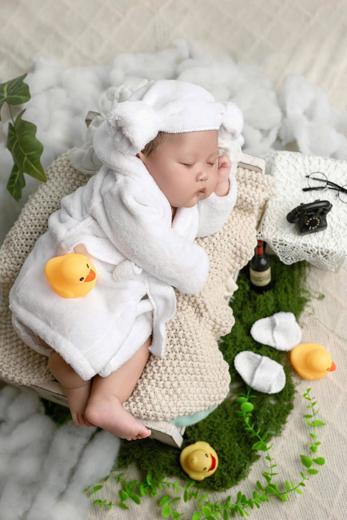Bé sơ sinh ngủ trong trang phục trắng bên thú bông nhỏ
