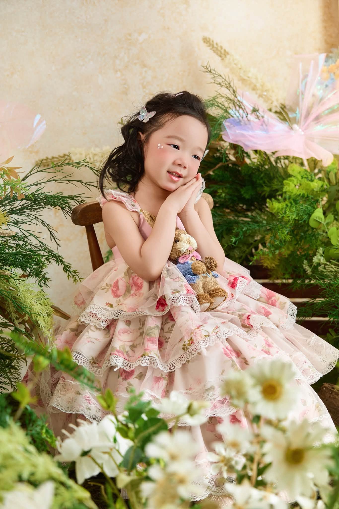 Bé gái trong váy hoa giữa bối cảnh vườn hoa